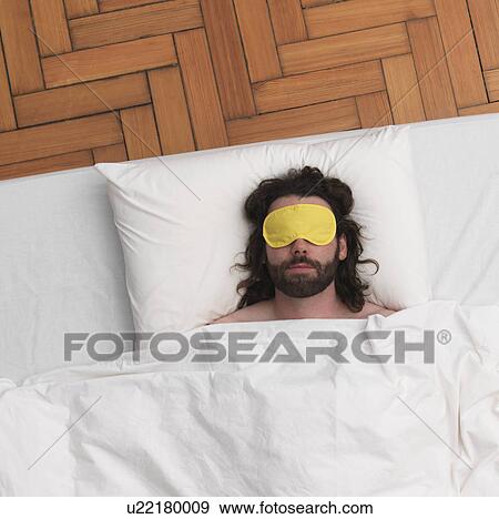 Stock Photo - Man sleeping, wearing eye-mask. Fotosearch