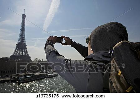 Stock Photography - Man taking photo of eiffel tower. Fotosearch