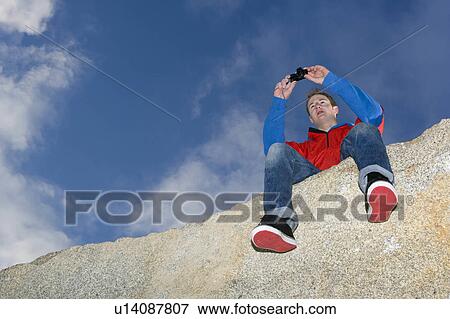 Stock Photo - man taking picture on mountain top. Fotosearch