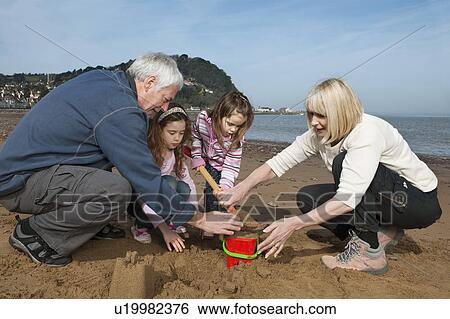 Stock Photograph - mature couple with children on beach. Fotosearch