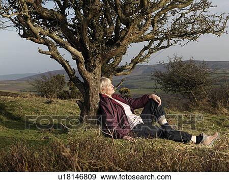 Stock Photo - mature woman leaning against tree. Fotosearch
