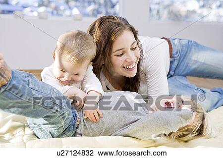 Stock Image - Mother and children cuddling and playing. Fotosearch