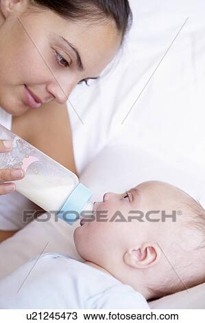 Stock Image - Mother giving the bottle to her baby. Fotosearch
