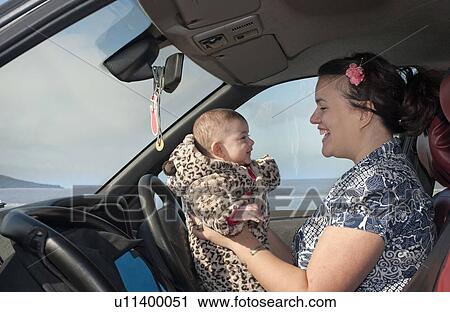 Stock Image - mother in car holding baby. Fotosearch