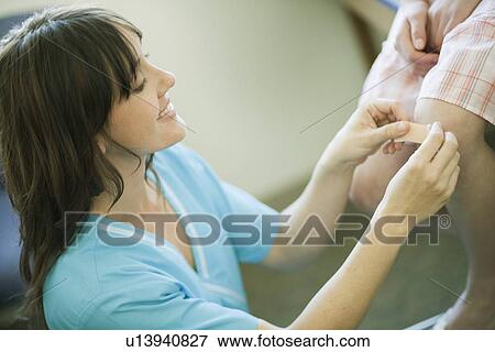 Stock Photo - Nurse putting plaster/bandage on knee. Fotosearch