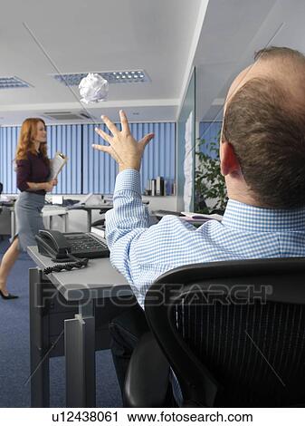 Stock Image - Office worker throwing paper ball. Fotosearch
