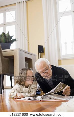 Stock Image - old man reading book to young girl. Fotosearch