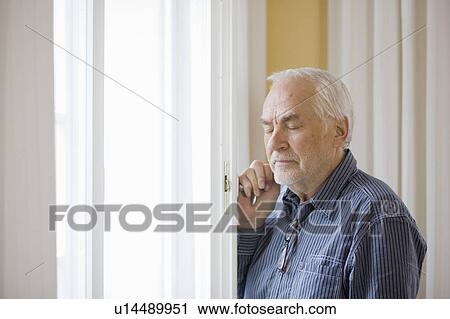 Stock Image - old man standing at window. Fotosearch