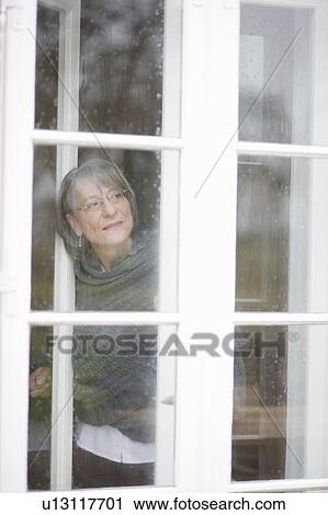 Stock Image - old woman looking out a window. Fotosearch