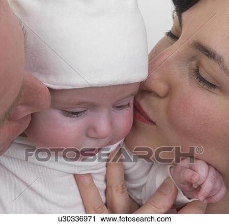 Stock Image - Parents kissing baby, close-up. Fotosearch