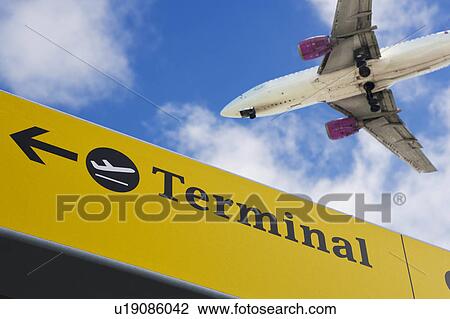 Stock Image - Plane flying over 'terminal' sign. Fotosearch