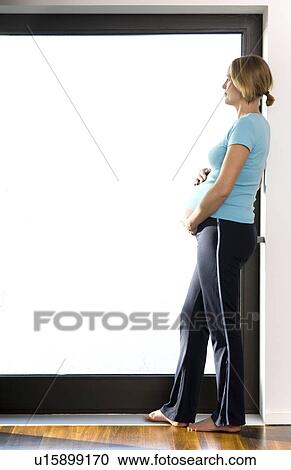 Stock Image - pregnant woman looking out a window. Fotosearch