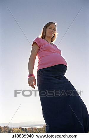 Stock Image - pregnant woman standing outside. Fotosearch