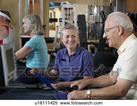 Stock Photography - senior male at gym with instructor. Fotosearch