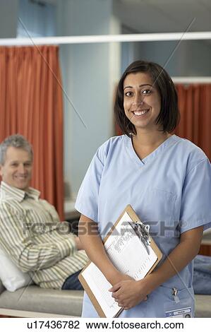 Smiling nurse, patient behind View Large Photo Image Stock Image - Smiling nurse, patient behind. Fotosearch
