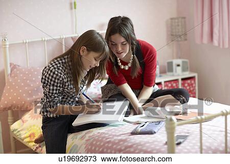 Stock Image - Teenage girls doing homework. Fotosearch
