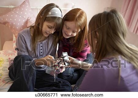 Stock Image - Teenage girls playing with mobile phones. Fotosearch