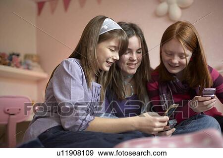 Teenage girls playing with mobile phones View Large Photo Image Stock Photo - Teenage girls playing with mobile phones. Fotosearch
