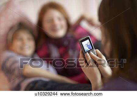 Picture - Teenage girls taking photo on phone. Fotosearch