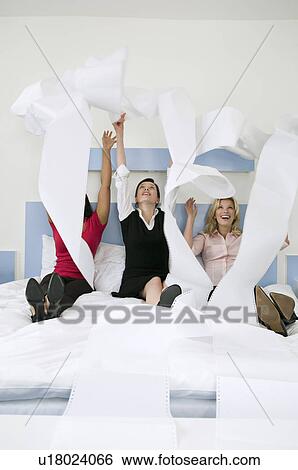 Stock Photograph - Three female colleagues throwing paper. Fotosearch