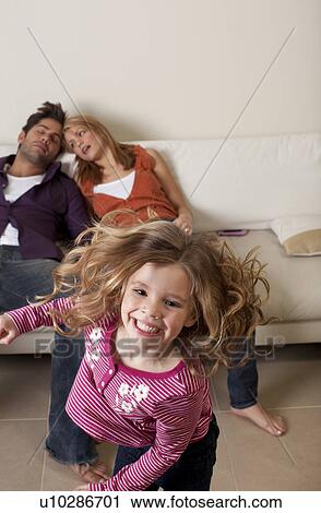 Stock Image - tired couple asleep while child dances. Fotosearch