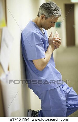 Tired Male surgeon leaning on wall View Large Photo Image Picture - Tired Male surgeon leaning on wall. Fotosearch