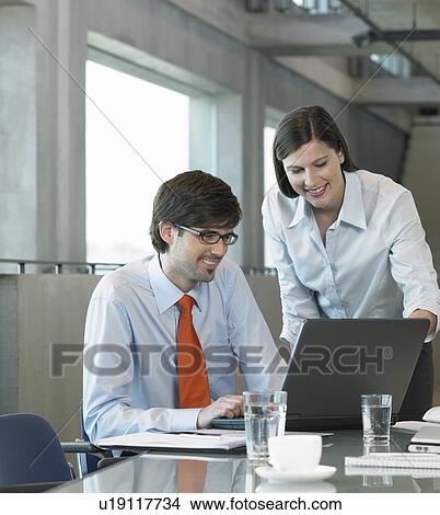 Two Businesspeople looking on laptop View Large Photo Image Picture - Two Businesspeople looking on laptop. Fotosearch
