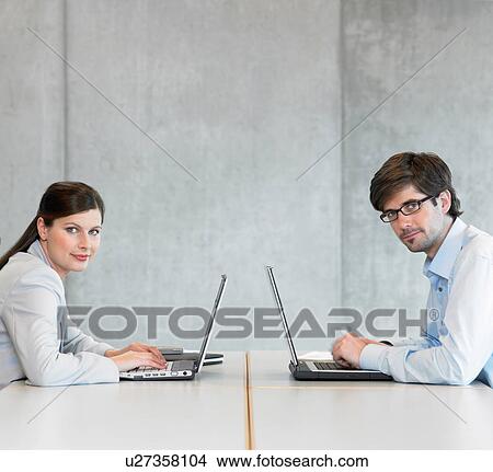 Two Businesspeople using laptops View Large Photo Image Picture - Two Businesspeople using laptops. Fotosearch