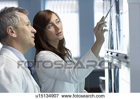 Two doctors looking at x-rays View Large Photo Image Stock Photo - Two doctors looking at x-rays. Fotosearch
