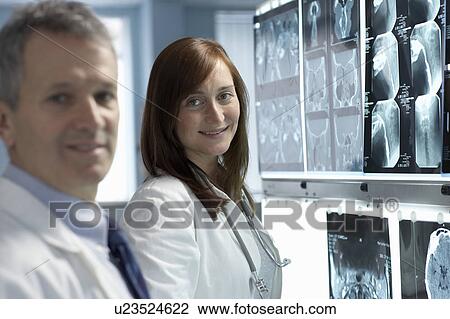 Two doctors, smiling, x-rays behind View Large Photo Image Stock Image - Two doctors, smiling, x-rays behind. Fotosearch