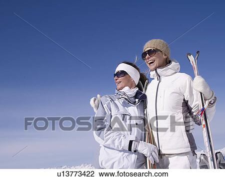 Stock Image - two women with skis smiling. Fotosearch