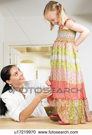 Stock Image - Woman adjusting a girl's dress. Fotosearch