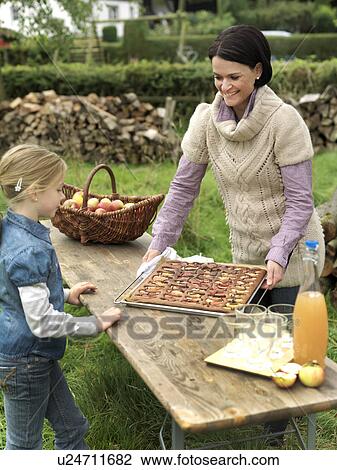 Stock Image - Woman and girl looking at applecake. Fotosearch