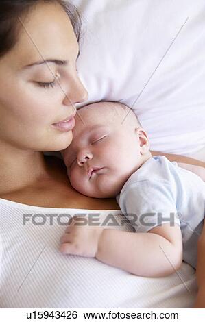 Woman and her baby sleeping in bed View Large Photo Image Stock Photograph - Woman and her baby sleeping in bed. Fotosearch