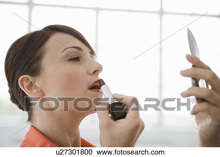 Woman applying lipstick in a mirror. View Large Photo Image Stock Image - Woman applying lipstick in a mirror.. Fotosearch