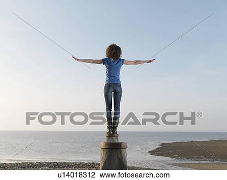 Stock Image - Woman balancing on wooden post. Fotosearch