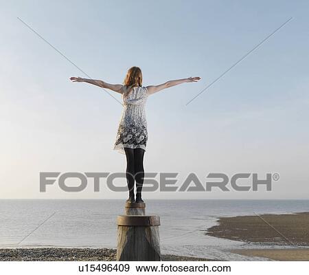 Stock Photo - Woman balancing on wooden post. Fotosearch