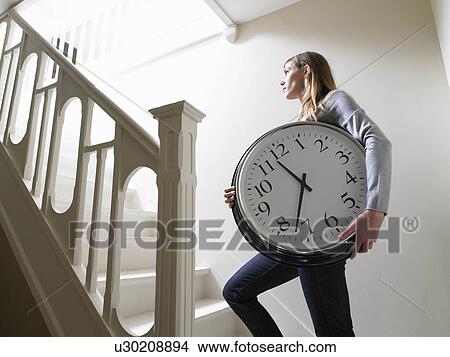Picture - Woman climbing the stairs with a clock. Fotosearch