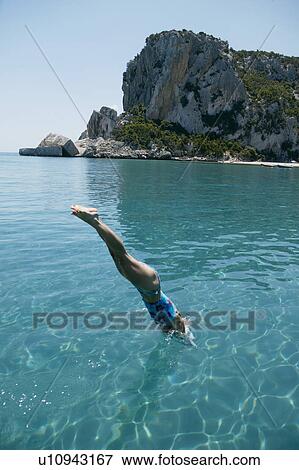 Stock Photo - Woman diving into blue water from boat. Fotosearch
