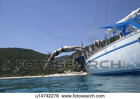Stock Photo - Woman diving into water from boat. Fotosearch