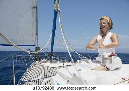 Stock Photo - Woman doing yoga on Sailing Boat. Fotosearch
