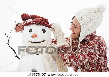 Stock Photo - woman dressing snowman. Fotosearch