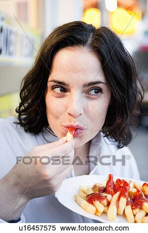 Stock Photography - Woman Eating French Fries. Fotosearch