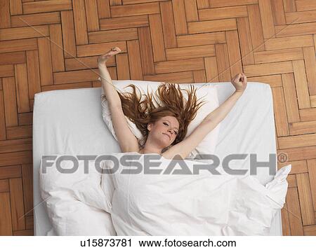 Stock Image - Woman having a stretch in bed. Fotosearch