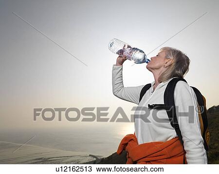 Stock Image - woman hiking drinking water. Fotosearch