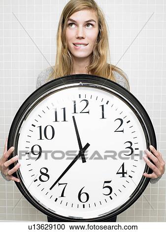 Stock Image - Woman holding a big clock. Fotosearch