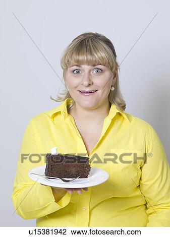 Stock Image - woman holding a plate of cake. Fotosearch