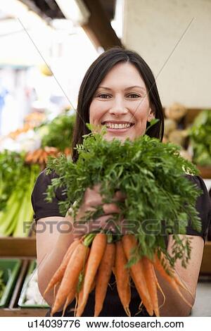 Stock Photograph - Woman holding bunch of carrots. Fotosearch
