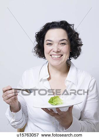 Stock Photo - woman holding plate with leaf of salad. Fotosearch