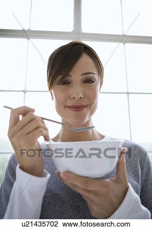 Stock Image - Woman holding spoon and bowl.. Fotosearch